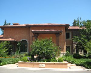 tan house with bush in front of the entryway