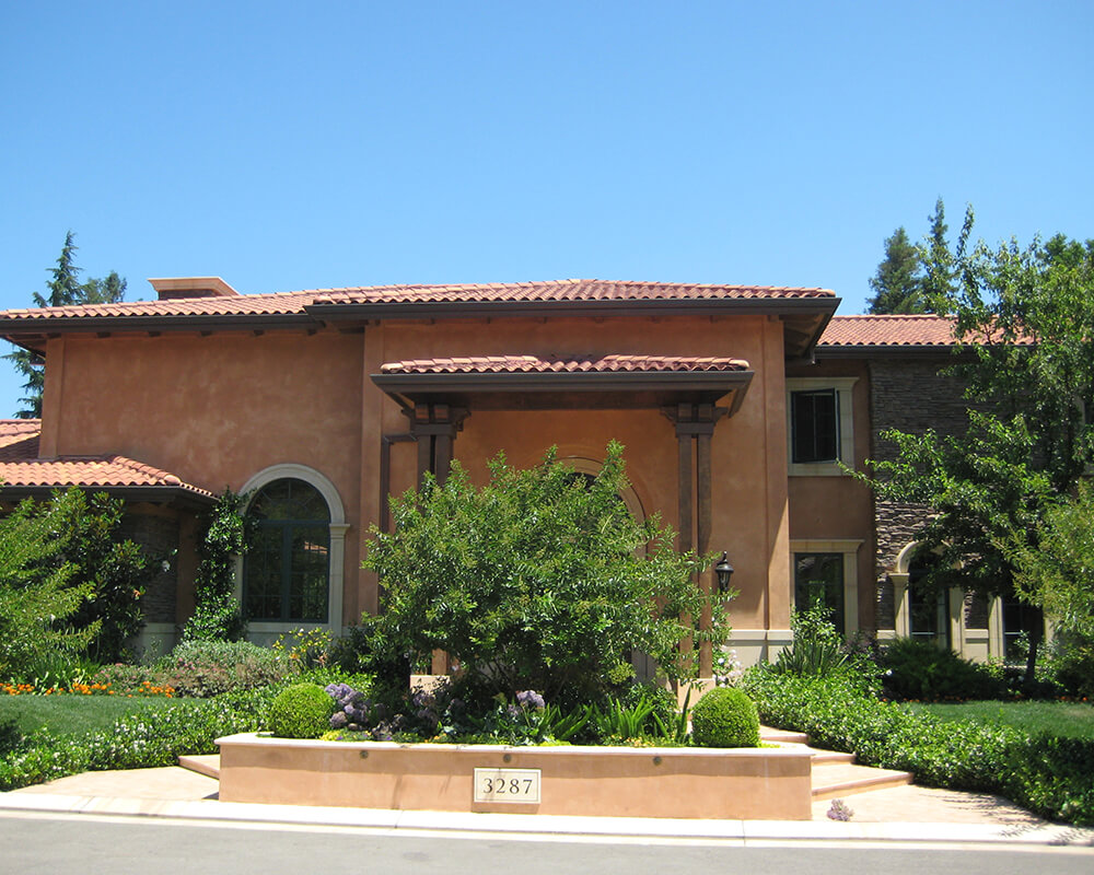 tan house with bush in front of the entryway