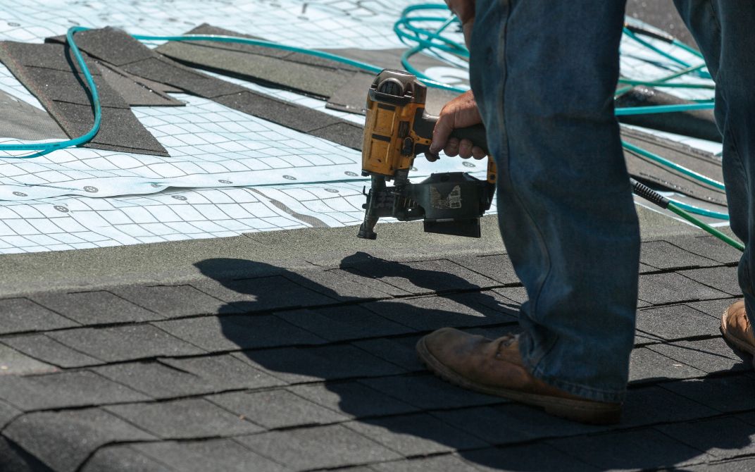 close up of Worker's work boots and drill on the roof as a roof is being installed