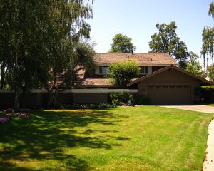 brown house with large green yard and willow tree