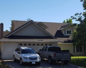 an suv and a truck sit in the driveway of a home with a new roof