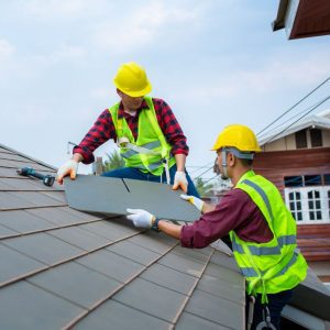 two men in red wearing high vis install a roof