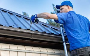 Man in blue t-shirt works on a roof