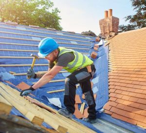 man in high vis hammers nail into roof