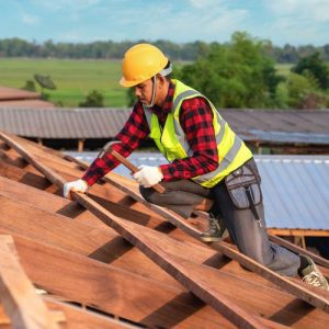 man in plaid and high vis with a hammer on the roof