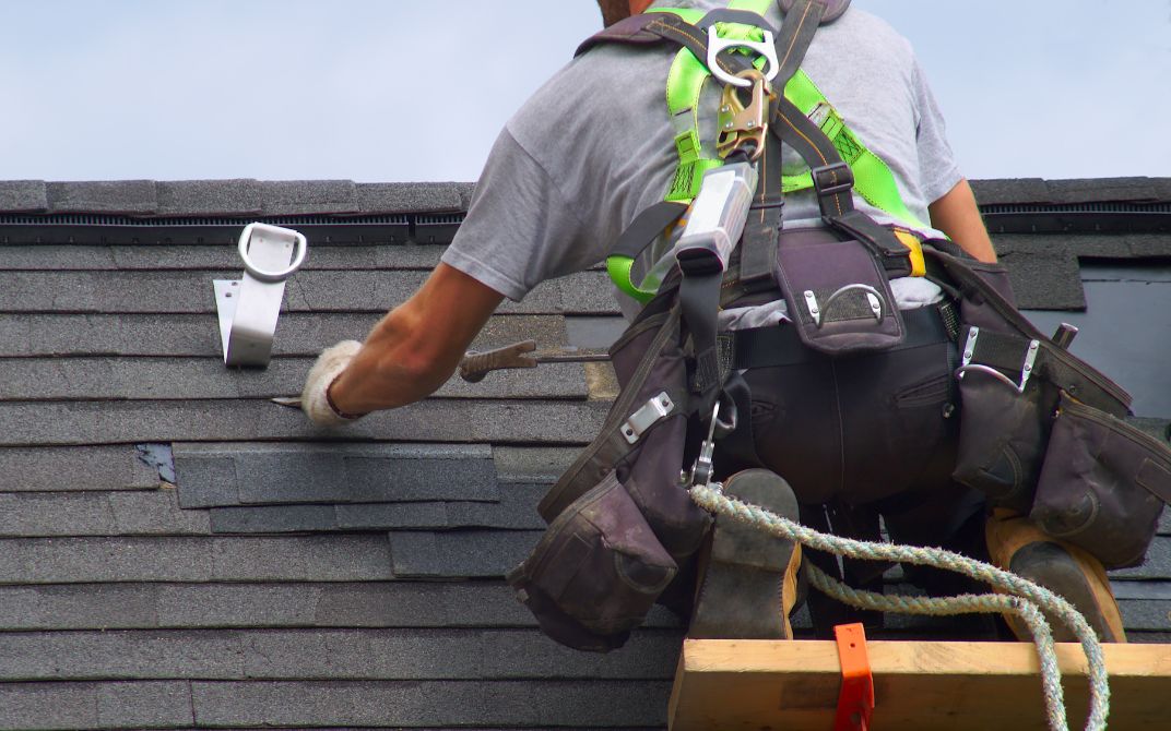 man in grey shirt works on a roof