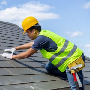 man lays shingles on a roof