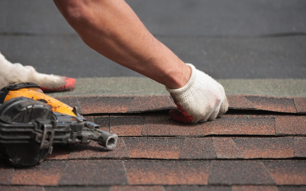 gloved hands are shown laying down parts of a roof