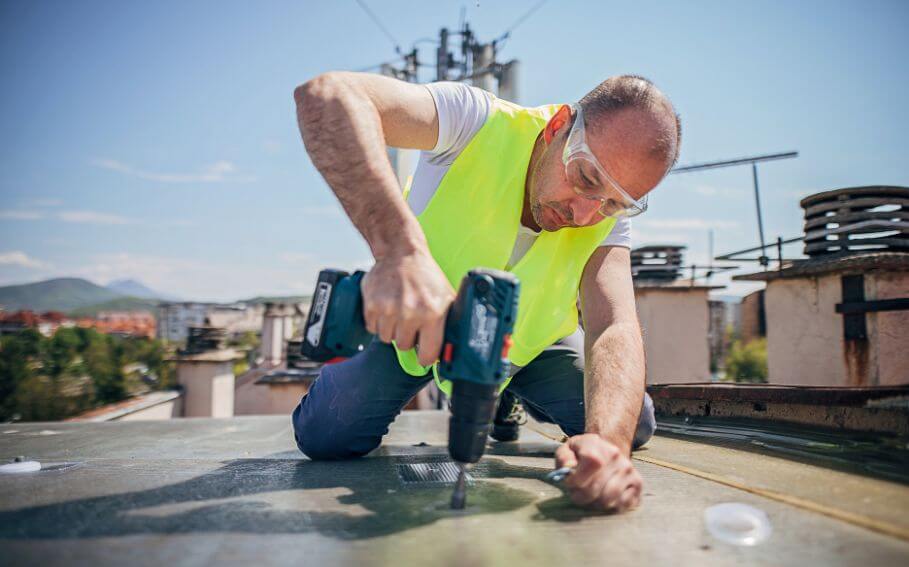 a man in safety vest and safety glasses using a drill