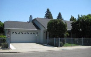 a home with a fence and garage in front of it