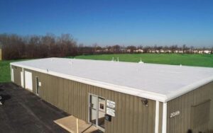 a large building with a white roof and green grass