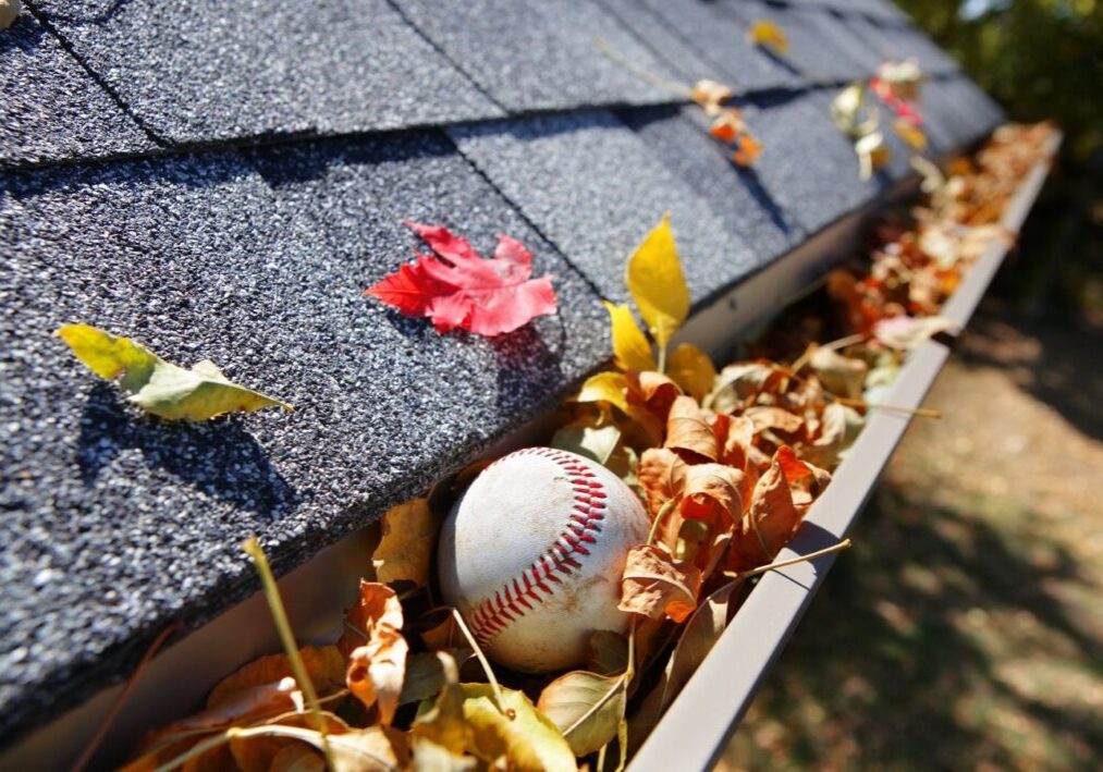 a baseball is sitting on the roof of a gutter